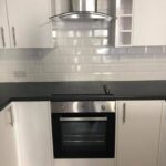 Modern kitchen installation with white cabinets, stainless steel oven, and subway tile backsplash.