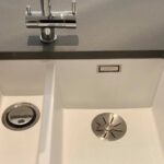 Close-up of a modern kitchen sink installation with a stainless steel faucet.