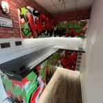 Modern kitchen installation with street art-style graffiti wall mural and white subway tile backsplash.