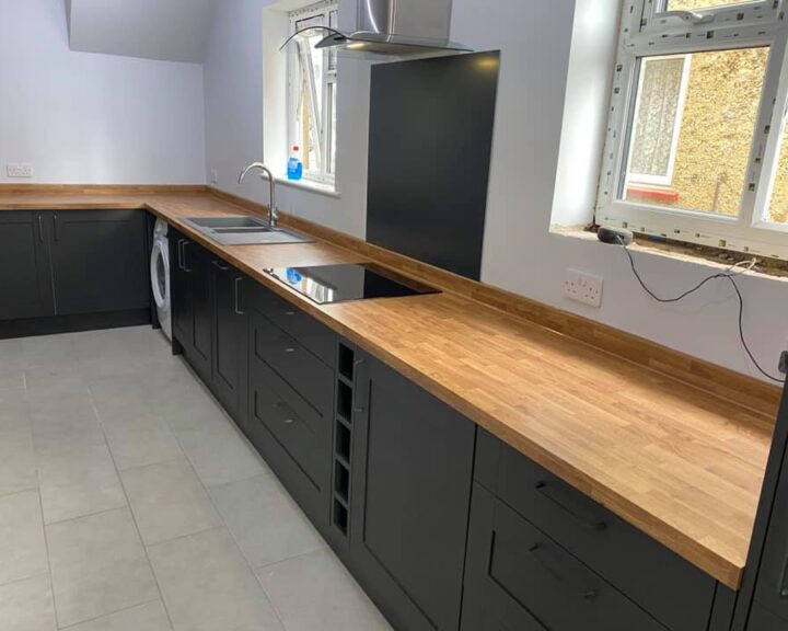 A black kitchen with wooden worktops and a sink.