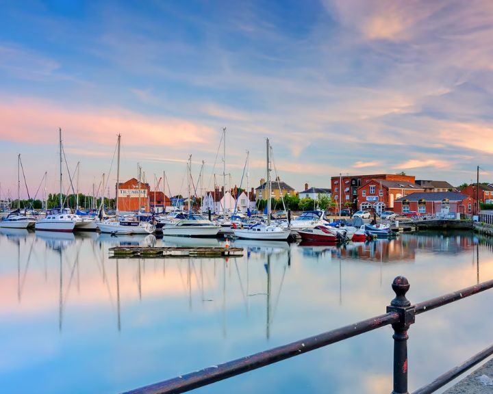 Tranquil marina at dusk, with still water reflecting moored sailboats and pastel sky, reminding one of a brilliantly executed kitchen installation where each element is perfectly placed.