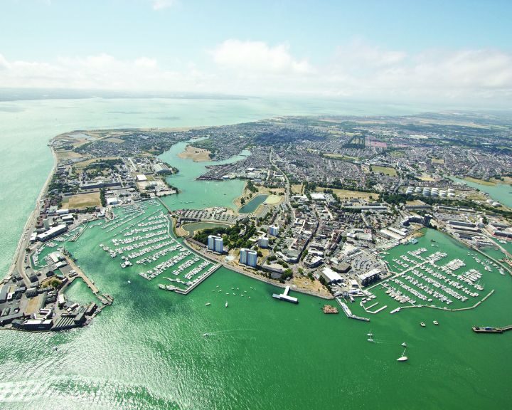 Aerial view of a coastal city with marinas, boats, and an elaborate kitchen design showcased on the waterfront.