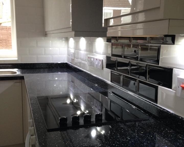 Modern kitchen design with black countertops and white cabinetry.