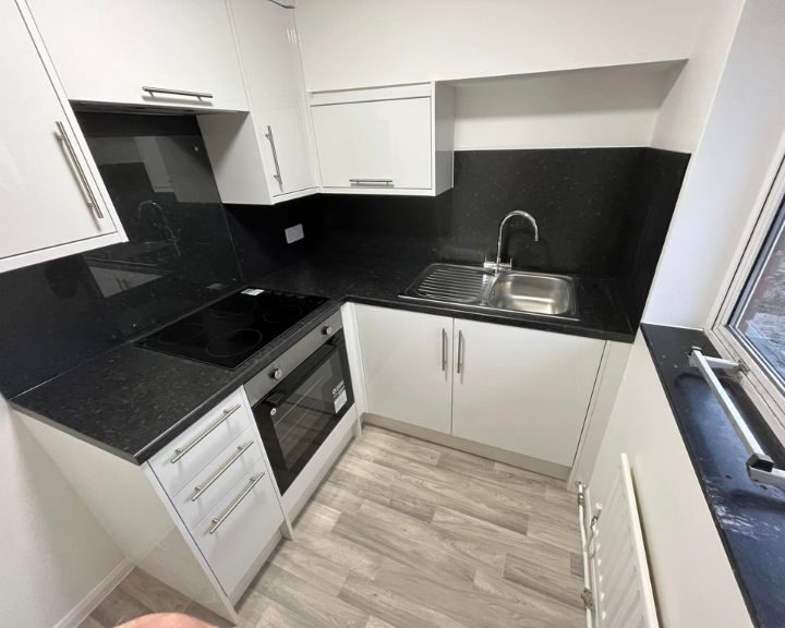 Modern kitchen with black countertops and white cabinets.