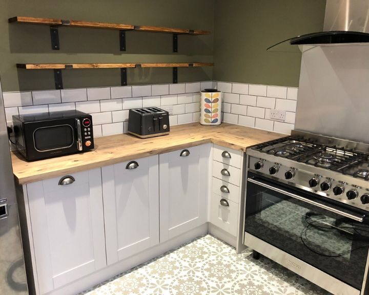 A modern kitchen design with white cabinetry, wooden countertops, subway tile backsplash, and stainless-steel appliances.