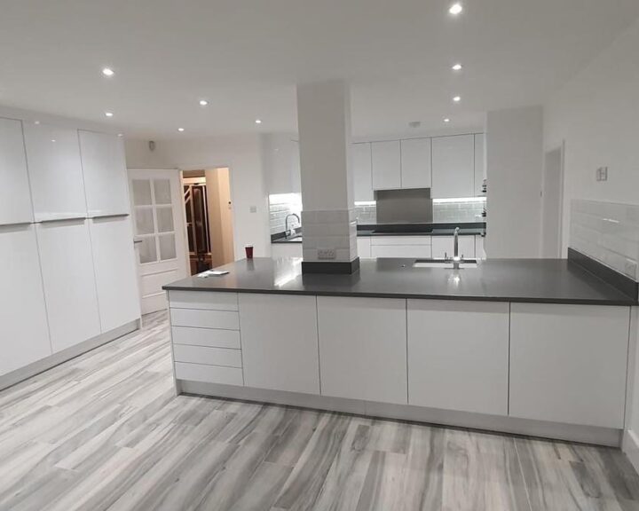 Modern kitchen with white cabinetry, gray countertops, and kitchen tiling.