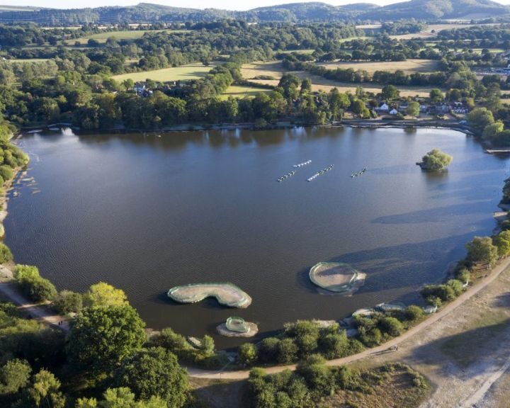 Aerial view of a rowing team practicing on a calm river with surrounding greenery, reminiscent of the tranquility often sought in kitchen design.