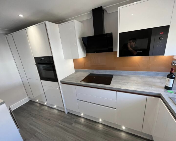 Modern kitchen with white cabinetry, built-in appliances, and a wood countertop, expertly installed by a professional kitchen fitter.