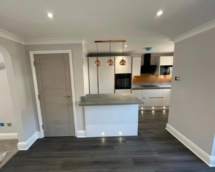 Modern kitchen design with an island, copper pendant lights, and integrated appliances.